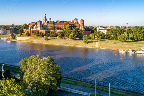 Royal Wawel Cathedral and castle in Krakow, Poland. Aerial view in sunset light. Vistula River, tourist boats, canoes, riverbanks with trees, parks, promenade and  walking people