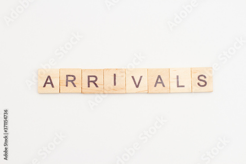 Word ARRIVALS made from wooden cubes on white. Travel concept.