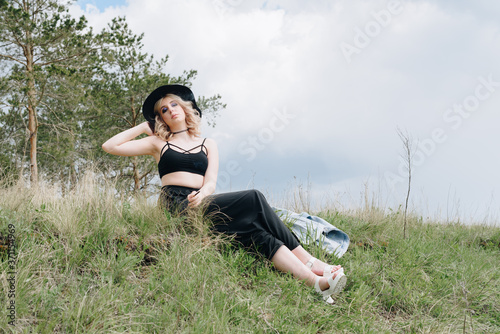 beautiful young woman in black against a landscape of sky and field