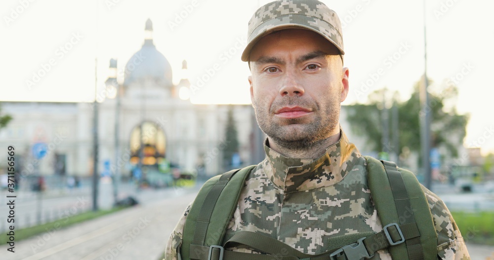 Portrait of serious Caucasian handsome young male soldier in cap with ...