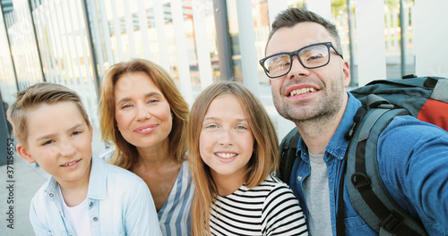 Foto POV of young Caucasian happy family with small teens kids having videochat, smiling and waving with hands outdoor