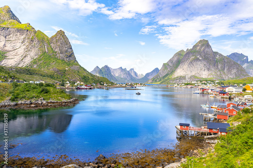 Reine in Lofoten Islands, Norway, with traditional red rorbu huts under blue sky with clouds. photo