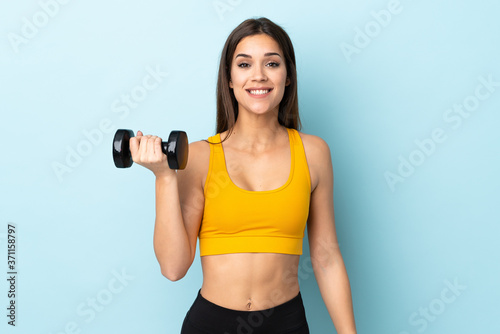Young caucasian woman making weightlifting isolated on blue background with surprise and shocked facial expression