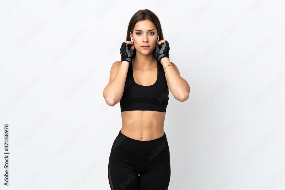 Young sport woman isolated on white background listening music and looking to the front