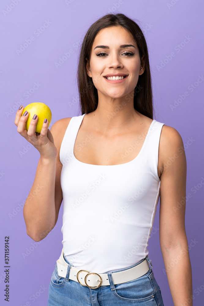 Young caucasian woman isolated on purple background with an apple Young caucasian woman isolated on purple background with an apple