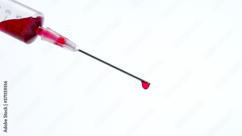 Drop of red blood from the tip of the syringe on white background. Drop of red blood from the tip of the syringe on white background.