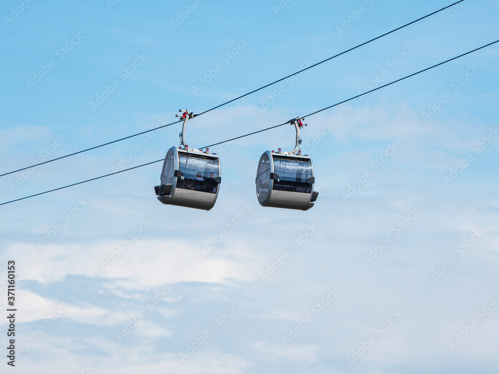 Two cable car cabins side by side against the blue sky