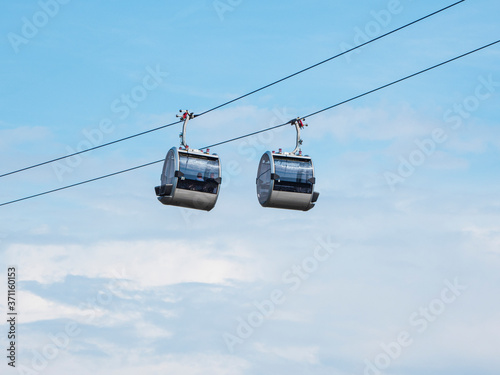 Two cable car cabins side by side against the blue sky