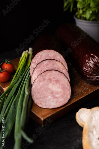  Sliced dry smoked sausage on a cutting board, focus on slices.