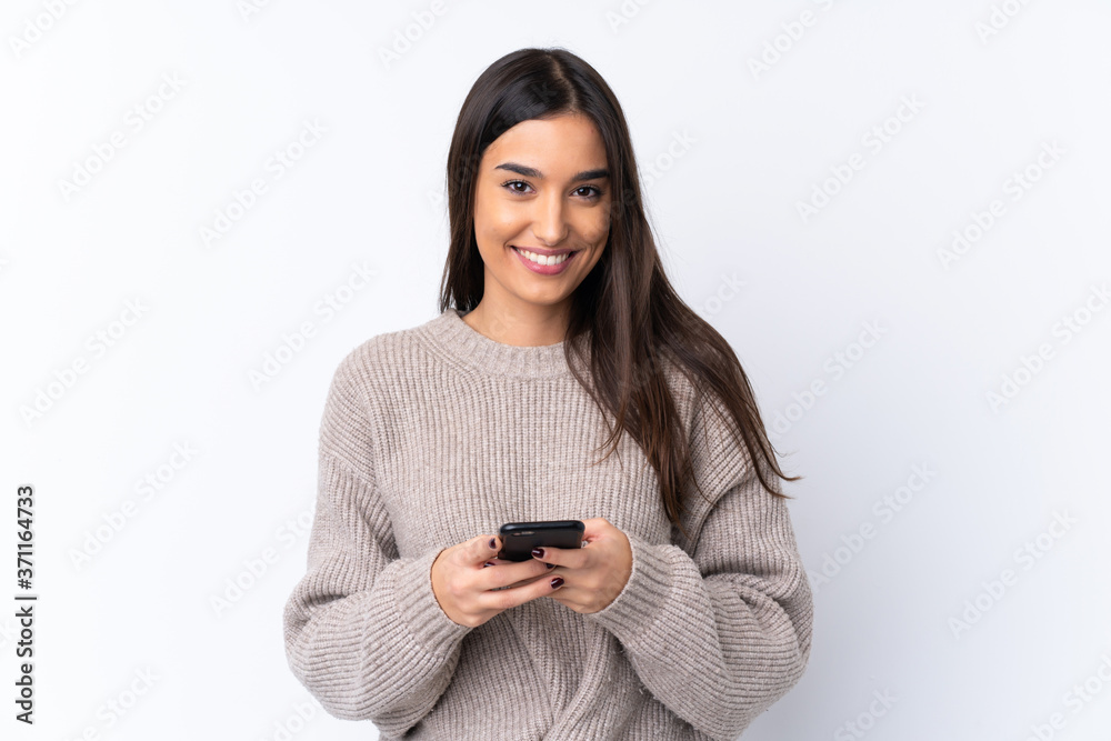 Young brunette woman over isolated white background sending a message with the mobile Young brunette woman over isolated white background sending a message with the mobile