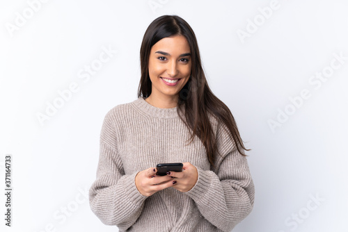 Young brunette woman over isolated white background sending a message with the mobile