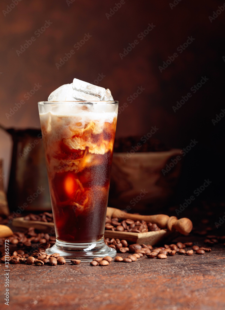 Ice coffee with cream being poured into it showing the texture and refreshing look of the drink. Ice coffee with cream being poured into it showing the texture and refreshing look of the drink.