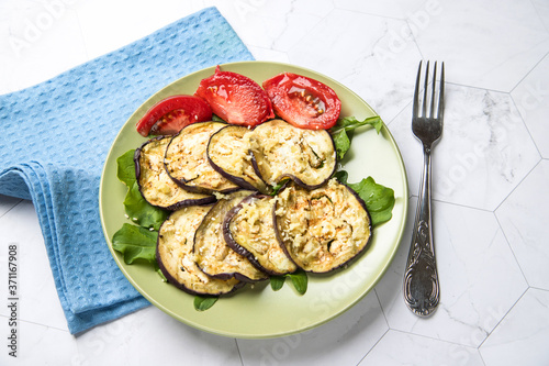 Grilled eggplant on a plate with tomatoes and herbs. Vegetarian food. Horizontal orientation