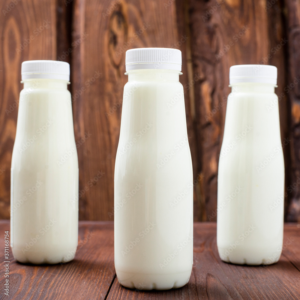 Bottles with milk, yogurt on a wooden background. Natural dairy products. Bottles with milk, yogurt on a wooden background. Natural dairy products.
