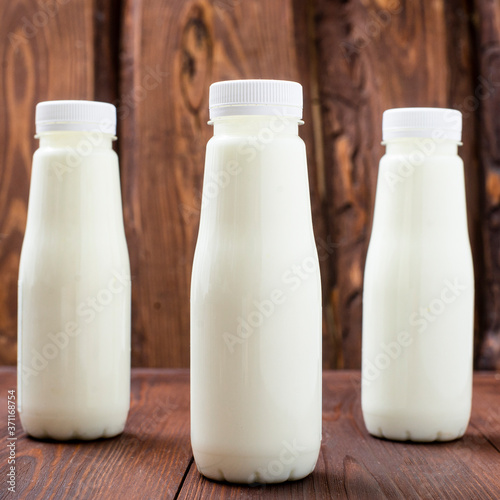 Bottles with milk, yogurt on a wooden background. Natural dairy products.