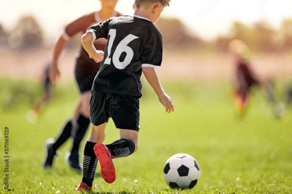 Fototapeta premium Kids in Soccer Club. Sports Summer Training Camp for School Children. Sports Summer Activity for Junior Level Athletes. Boy Running After Ball on Grass