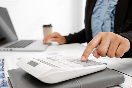 The hands of a male businesswoman use the calculator are analyzing and calculating the annual income and expenses in a financial graph that shows results To summarize balances overall in office © Orathai