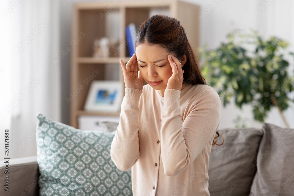 people and health problem concept - sick asian woman having headache at home people and health problem concept - sick asian woman having headache at home