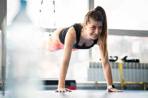 Fit pretty woman doing planks in gym using gym equipment