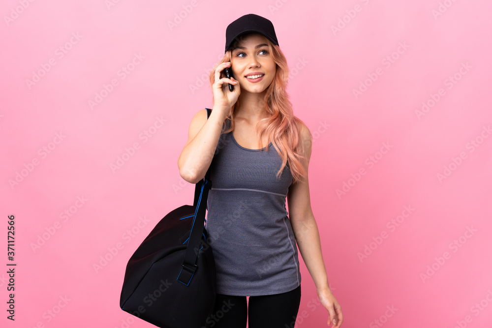 Teenager sport woman with sport bag over isolated background keeping a conversation with the mobile phone Teenager sport woman with sport bag over isolated background keeping a conversation with the mobile phone