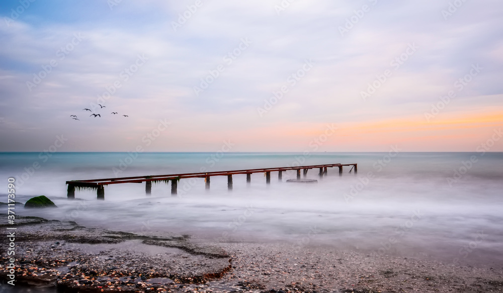 Fototapeta premium Old Worn Pier Columns, Logs of remains of the old, wooden pier, in the sea