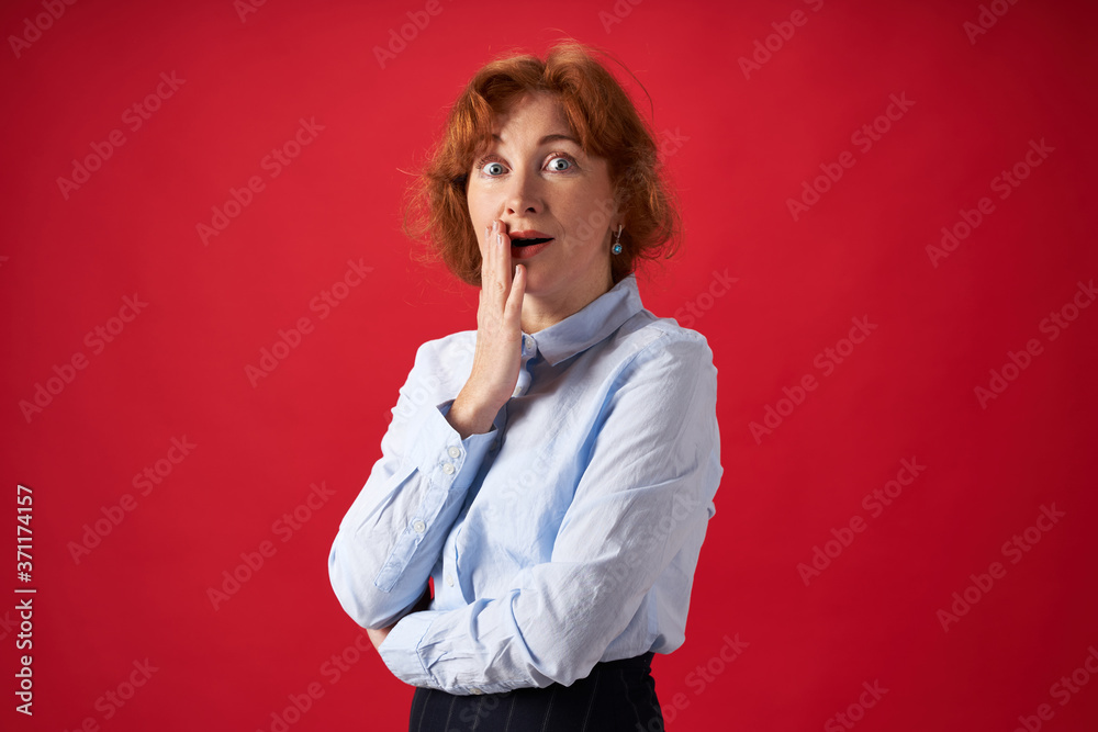 Beautiful redhead woman surprised on red background Beautiful redhead woman surprised on red background