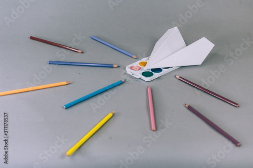 Back To School Concept. Paper airplane with paints on a gray background.