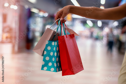Young and fashionable woman in a store with beautiful and bright gift bags in her hands.