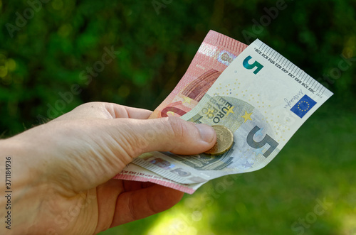 human hand holding euro banknotes (5 €, 10 € and 20 €): the man gives change or pays something