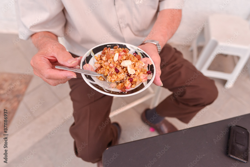 unrecognizable man eating typical Cyprus dish consisting of chickpeas, sesame, garlic, pomegranate and raisins