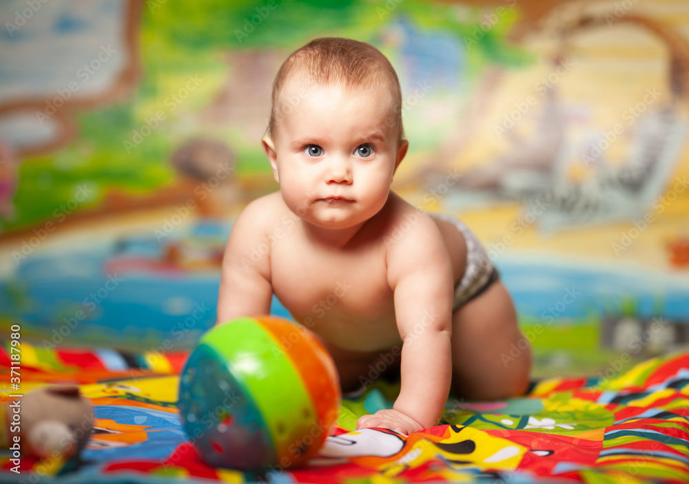 Obraz premium Portrait of a cheerful smiling caucasian little six-month-old girl playing in the childrens room with educational toys. Baby products concept
