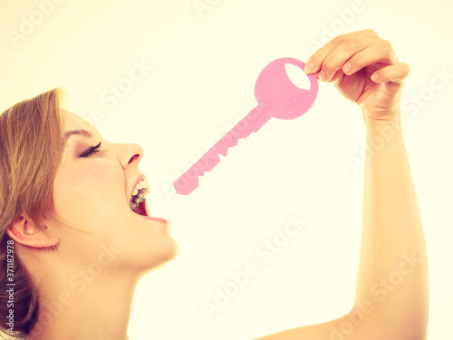 Blonde teenage girl biting pink key