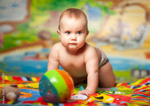 Portrait of a cheerful smiling caucasian little six-month-old girl playing in the childrens room with educational toys. Baby products concept