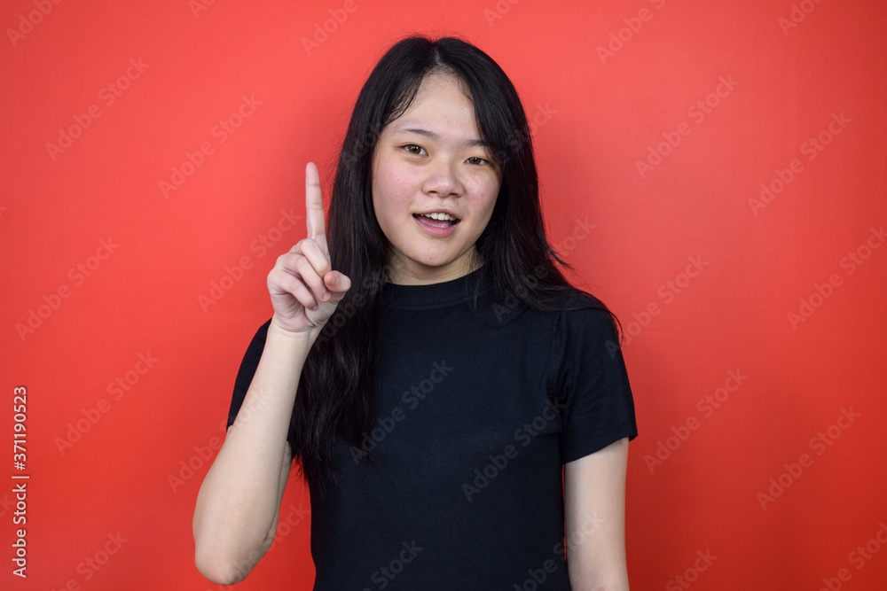 Portrait of Young beautiful asian woman using black T-shirt with red isolated background Portrait of Young beautiful asian woman using black T-shirt with red isolated background
