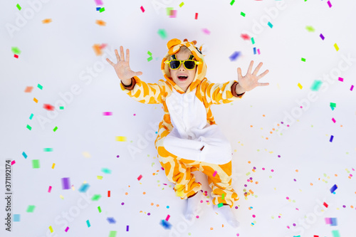 little boy in a fun bright giraffe costume on a white isolated background with confetti, children's birthday, place for text