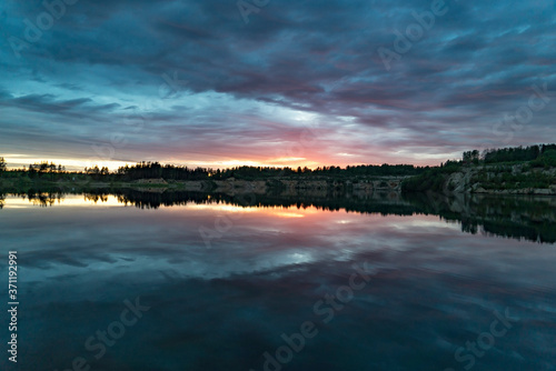 Colorful sunset with a mirror reflection in a forest lake .