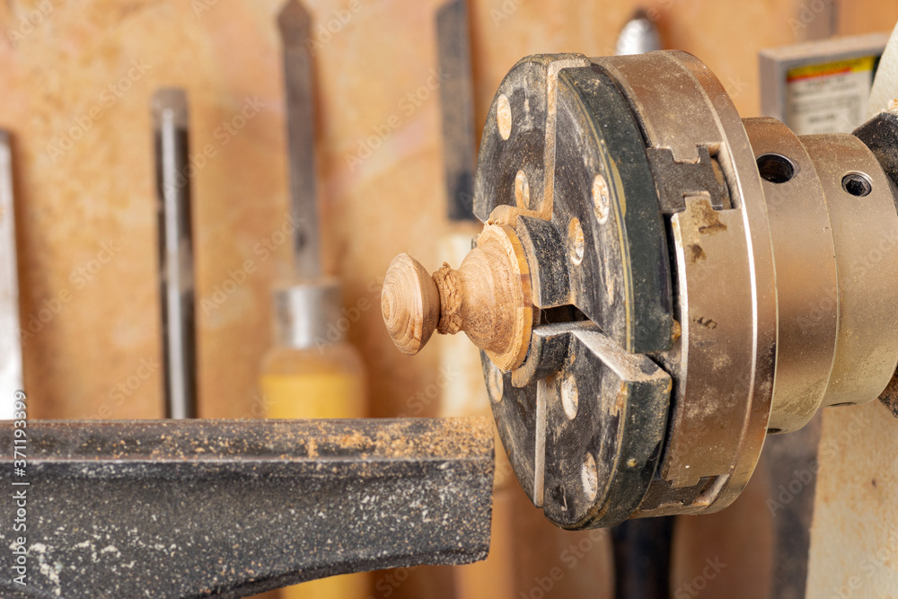Wooden part in the Chuck of a desktop lathe on the background of turning tools Wooden part in the Chuck of a desktop lathe on the background of turning tools