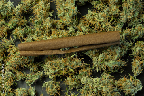 Cannabis rolled in blunt paper top view on marijuana buds background. Weed industry design photo