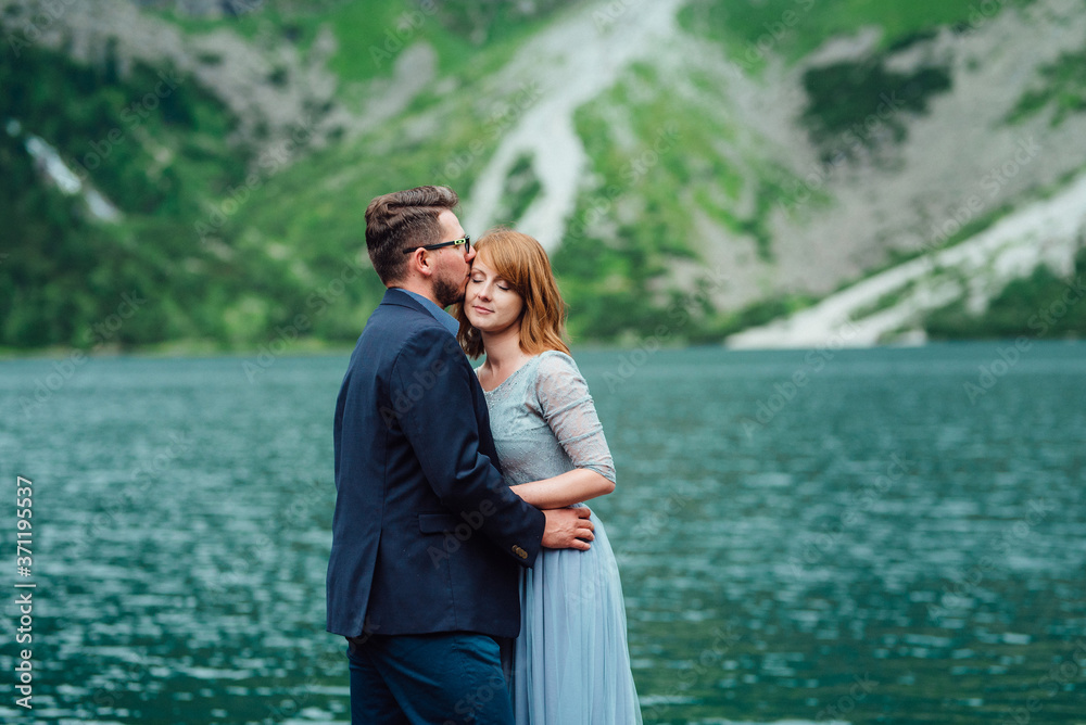 young couple on a walk near the lake surrounded by the mountains