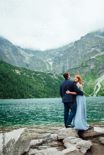 young couple on a walk near the lake surrounded by the mountains