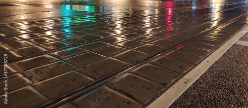 pavement wet from the rain with reflective lights in the evening