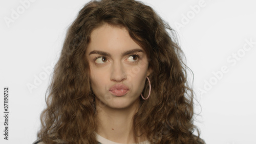 Capricious woman with pouting lips in studio. Portrait of confused girl face