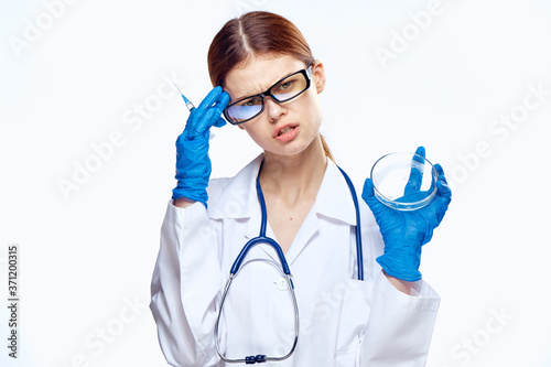 doctor woman in blue gloves with stethoscope nurse with glasses injection syringe laboratory light background