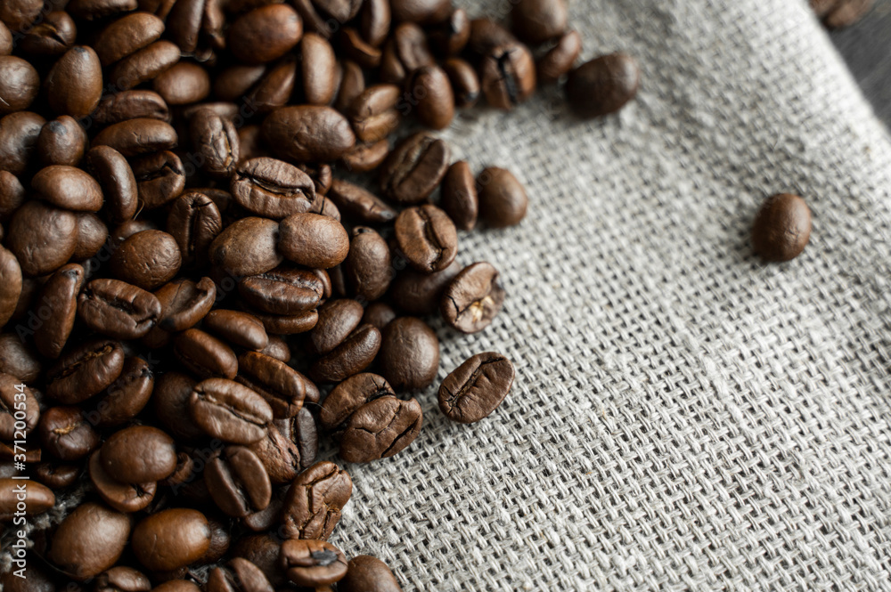 Coffee beans on a linen textile and on a wooden table background. Fresh arabica coffee beans. Coffee beans on a linen textile and on a wooden table background. Fresh arabica coffee beans.