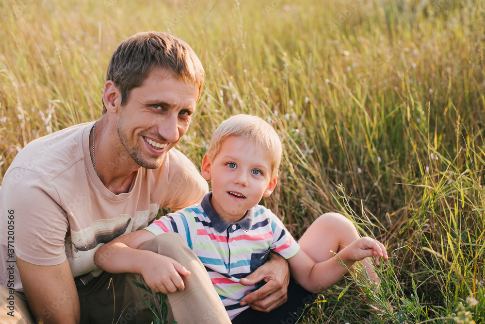 Fototapeta premium Happy young father and his little son in a field at sunset.