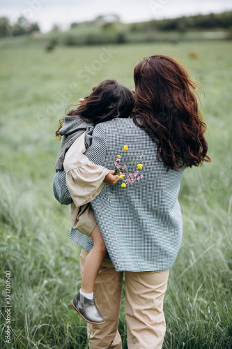 Portrait of hipster mother with daughter in her arms in the field. The family is having fun together