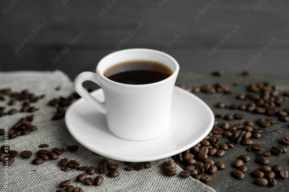 Coffee cup with roasted coffee beans on wooden table background. Mug of black coffe with scattered coffee beans on a wooden table. Fresh coffee beans. Coffee cup with roasted coffee beans on wooden table background. Mug of black coffe with scattered coffee beans on a wooden table. Fresh coffee beans.