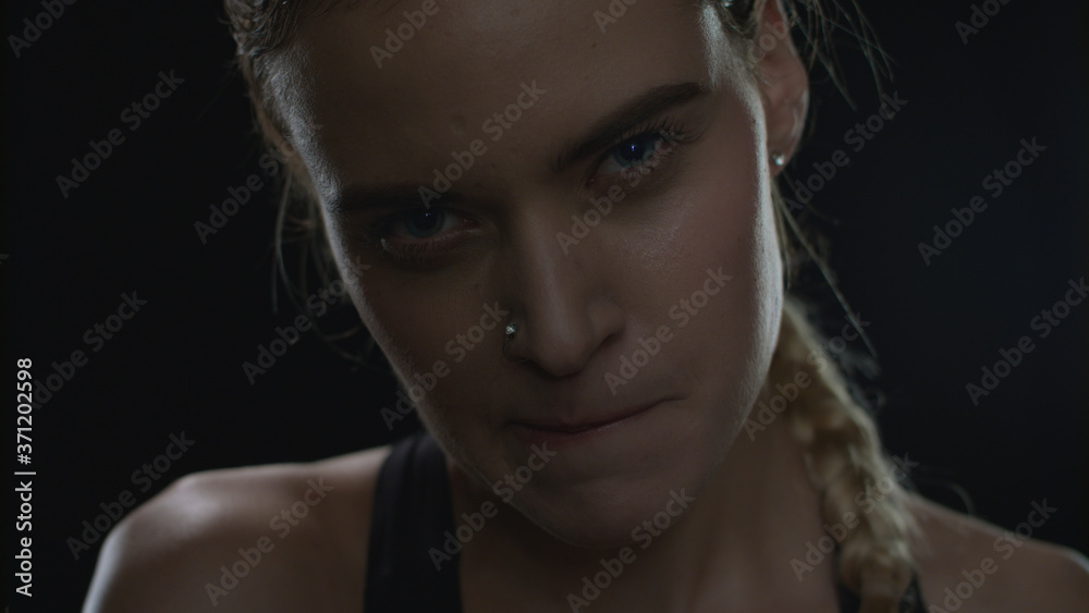 Fototapeta premium Aggressive woman biting lips looking to camera on black background