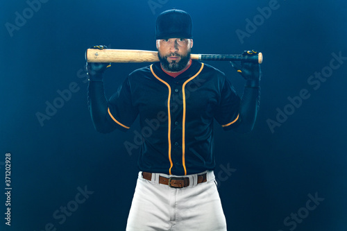 Photography Baseball player with bat on dark background. Ballplayer portrait.