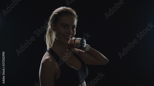 Sport woman smiling with dumbbell on shoulder in gym. Fitness model smiling © stockbusters